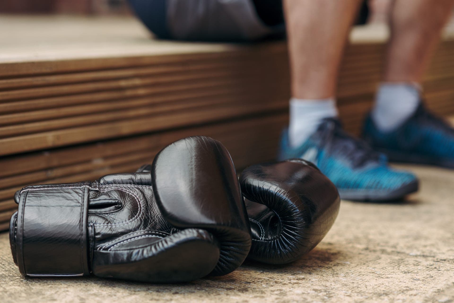 Black boxing gloves resting on a gym floor
