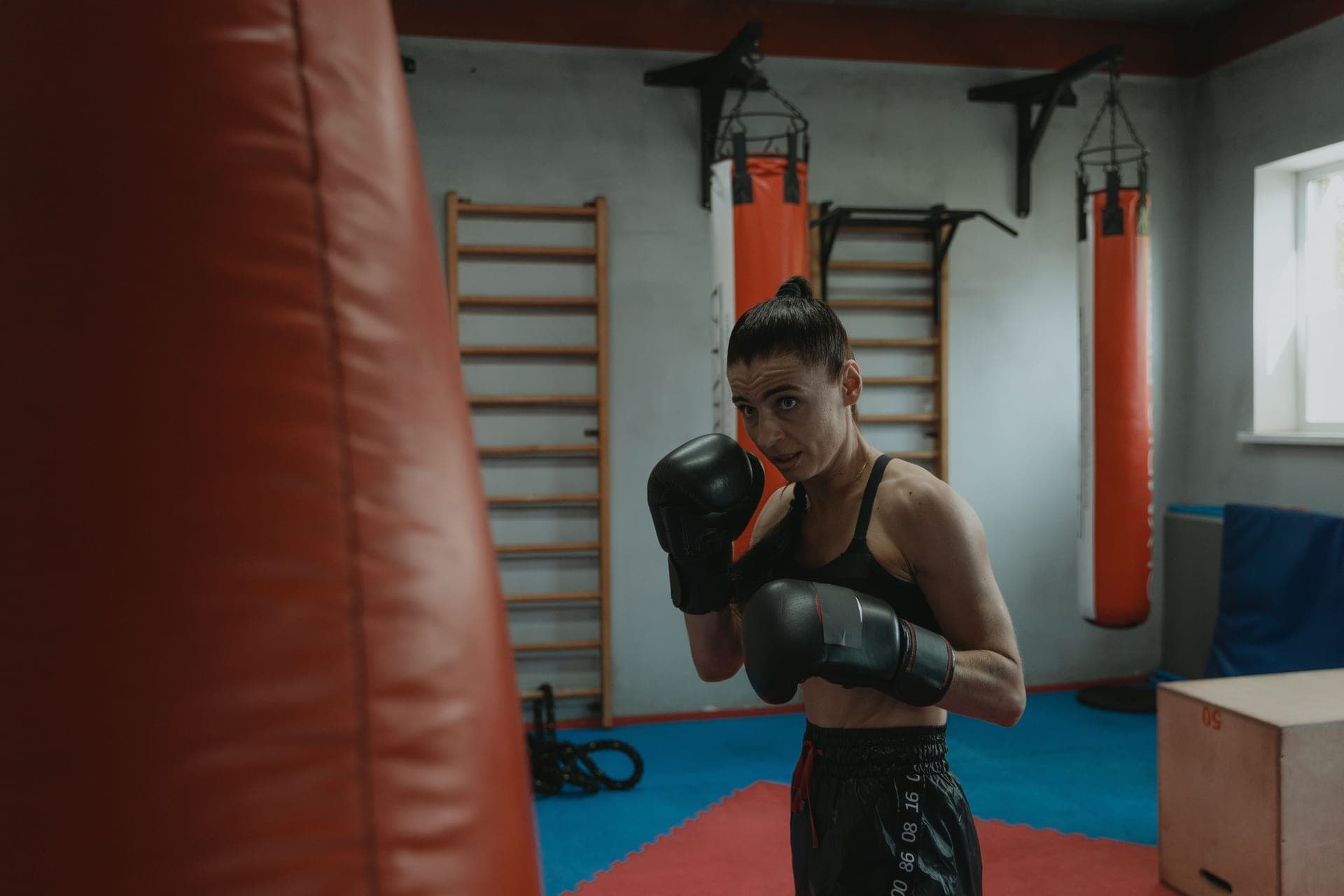 A boxer training with gloves in an indoor gym with punching bags