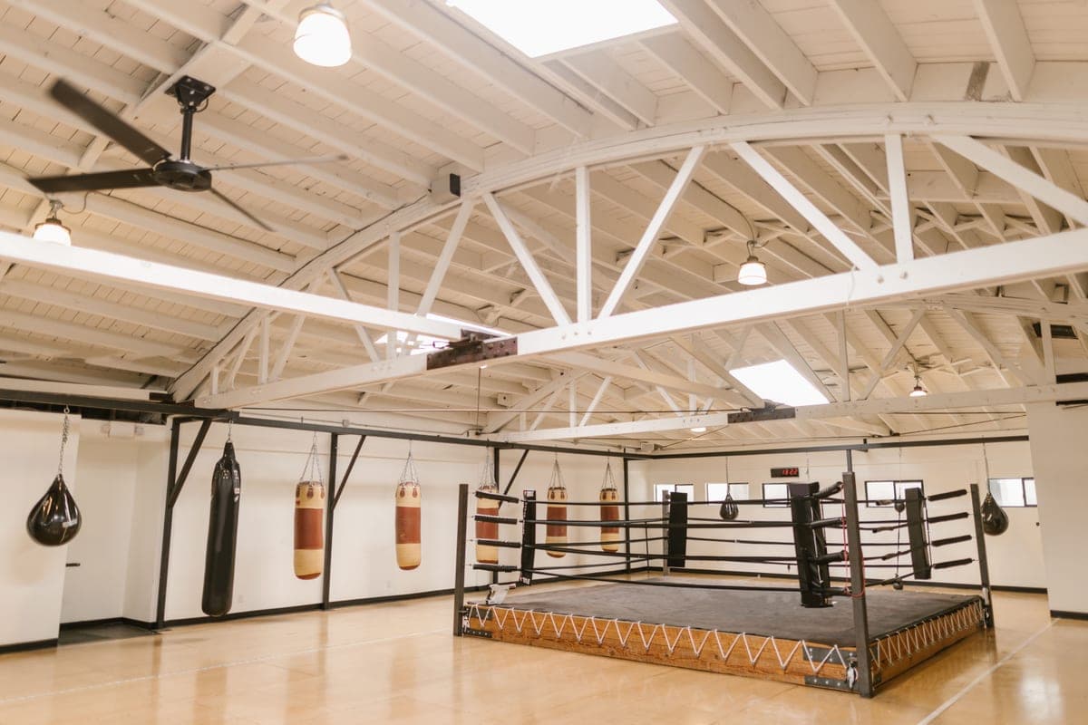 An empty boxing gym with hanging bags and a ring
