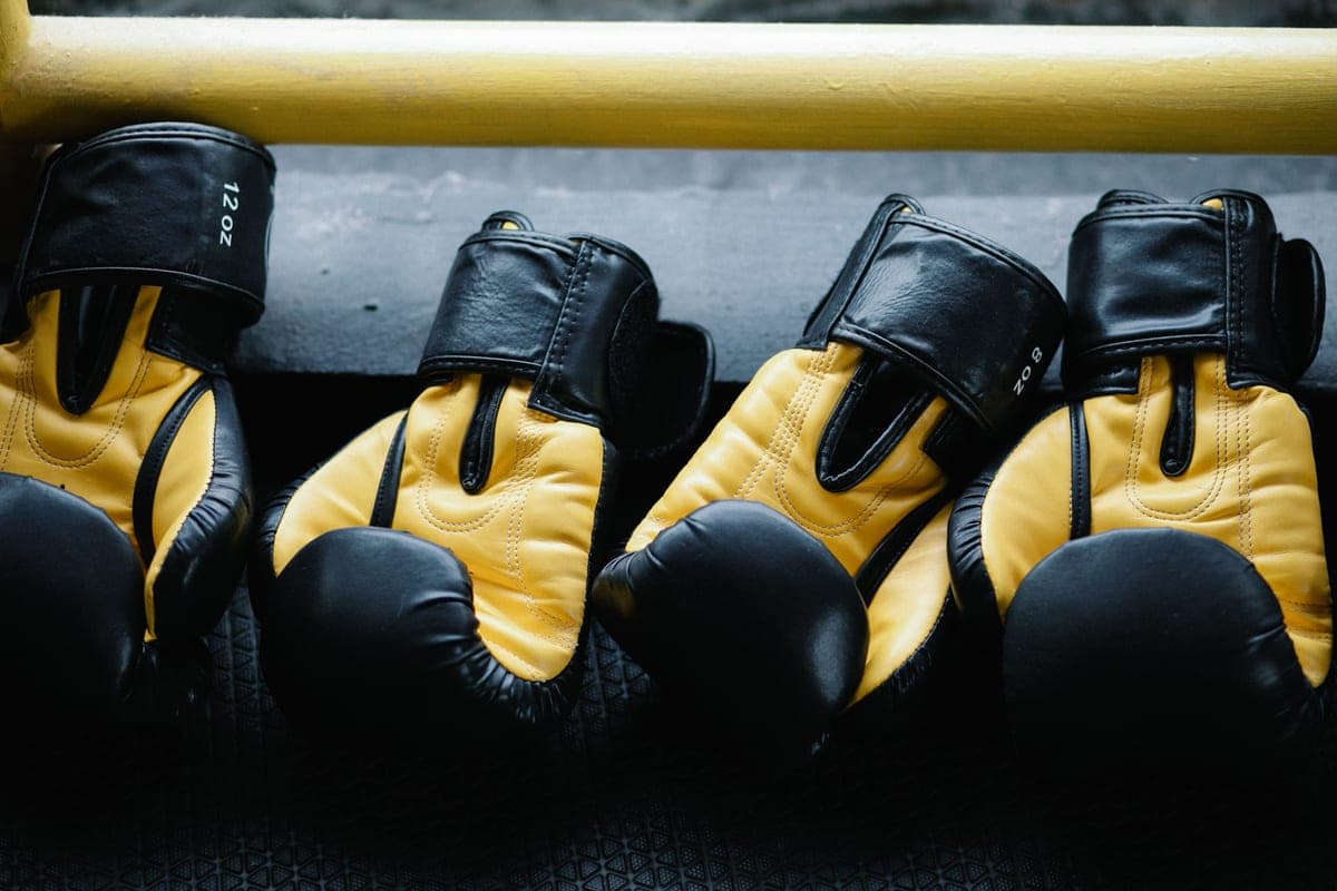A pair of yellow and black boxing gloves resting on a gym floor