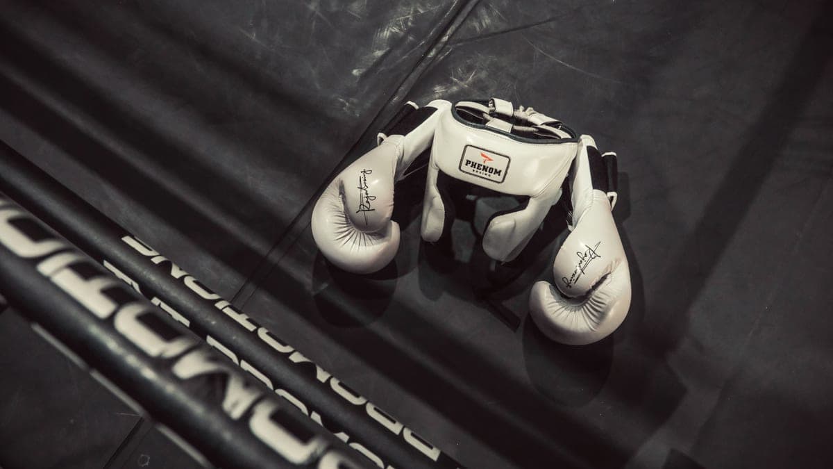 White boxing gloves and headgear resting on a boxing ring floor