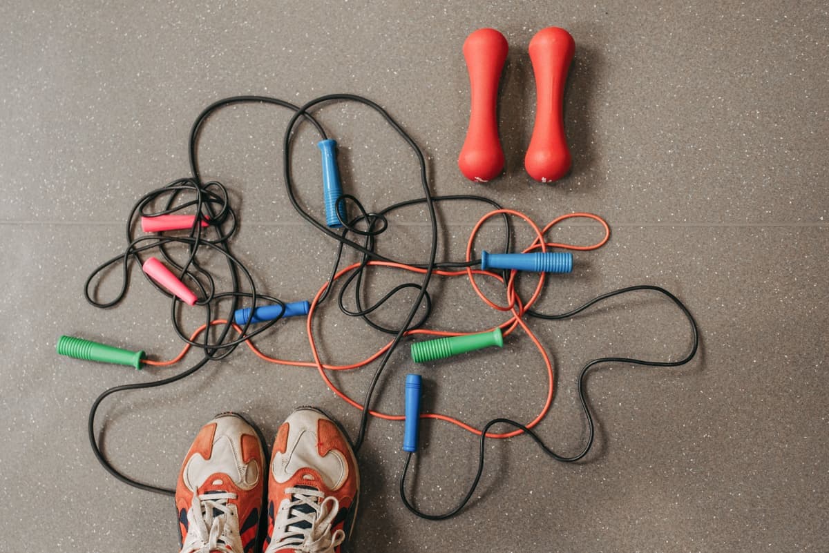 Jump ropes and dumbbells laid out on a gym floor