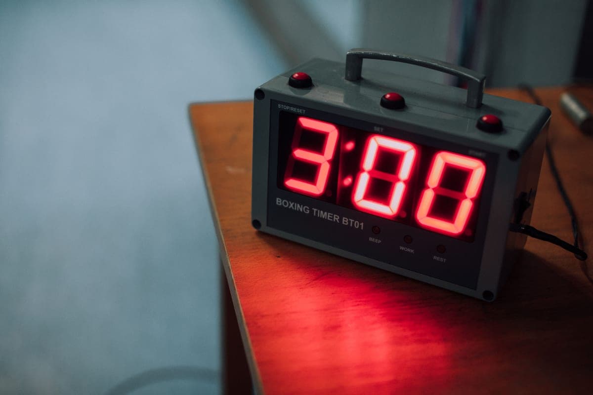 A digital boxing timer showing 3:00 on a wooden table